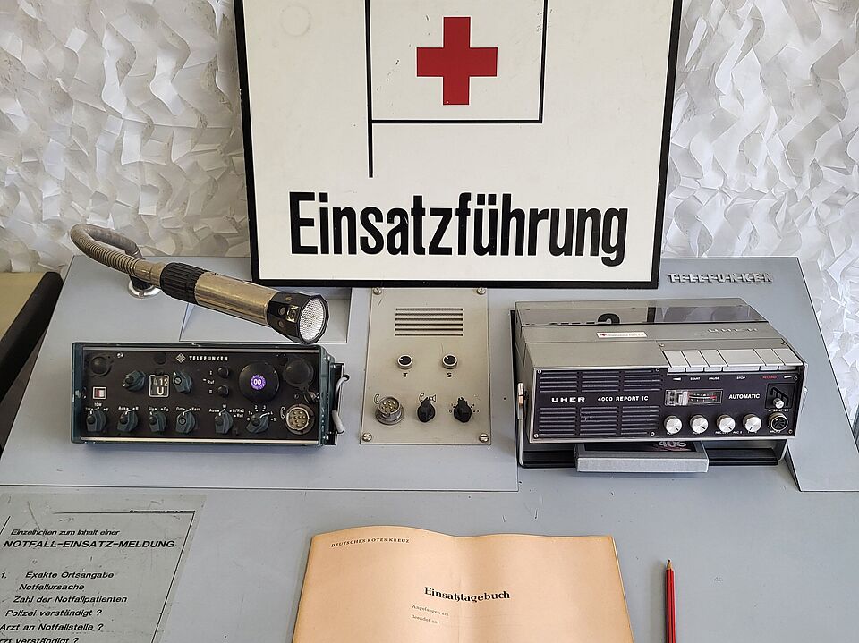 Historische Fernmeldezentrale mit Telefonhörern, Wählscheiben, Schaltern und Bedienfeldern sowie einem Sitzplatz für die Einsatzkommunikation.