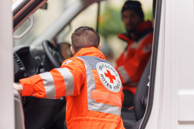 DRK Essen Mann in Dienstkleidung steigt in einen Rettungswagen ein.