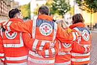 Vier Personen in Einsatzkleidung sind von hinten sichtbar und halten sich in den Armen.