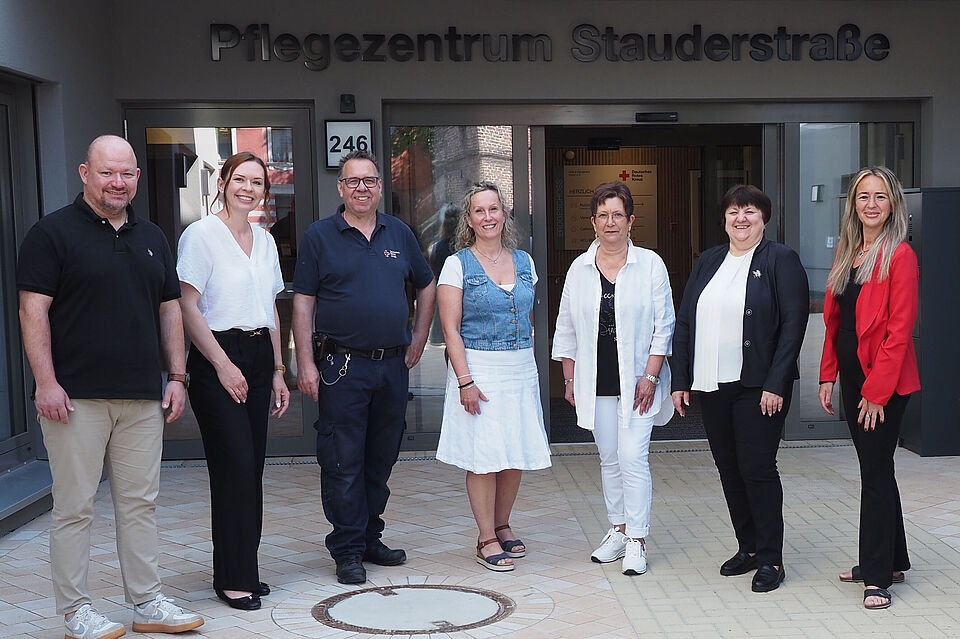 Team Pflegezentrum Staudertraße Acht Personen stehen in einem Halbkreis nebeneinander vor der Eingangstür des DRK-Pflegezentrums Stauderstraße.