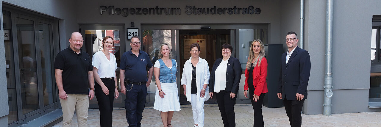 Team Pflegezentrum Staudertraße Acht Personen stehen in einem Halbkreis nebeneinander vor der Eingangstür des DRK-Pflegezentrums Stauderstraße.