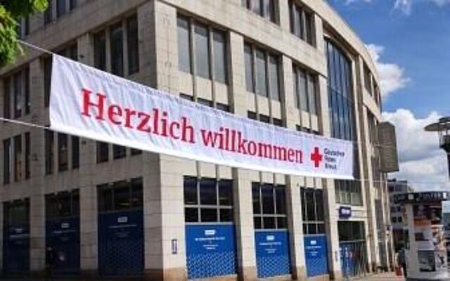 Ein Banner mit der Aufschrift "Herzlich willkommen" hängt über einer Fußgängerzone.