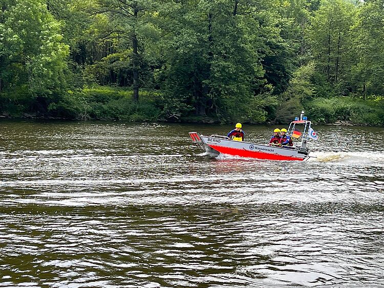 Ein Boot der Wasserwacht fährt mit drei Ehrenamtlichen der Wasserwacht übers Wasser.