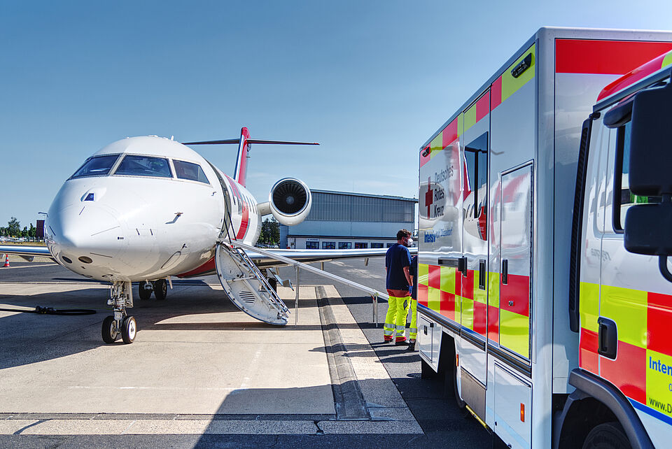 Flugdienst_Rollfeld Düsseldorf Ein Flugzeug steht neben einem Rettungswagen des DRK auf einem Flugfeld.