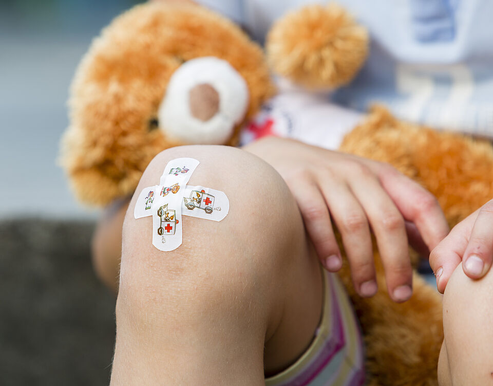 Symbolbild Erste Hilfe am Kind Das Bild zeigt ein Kinderpflaster auf einem Knie eines Kindes.