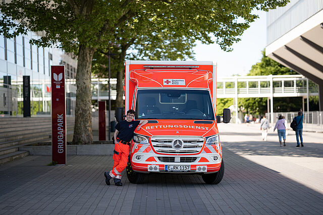 Ein junger Mann in Dienstkleidung lehnt an einem Rettungswagen.
