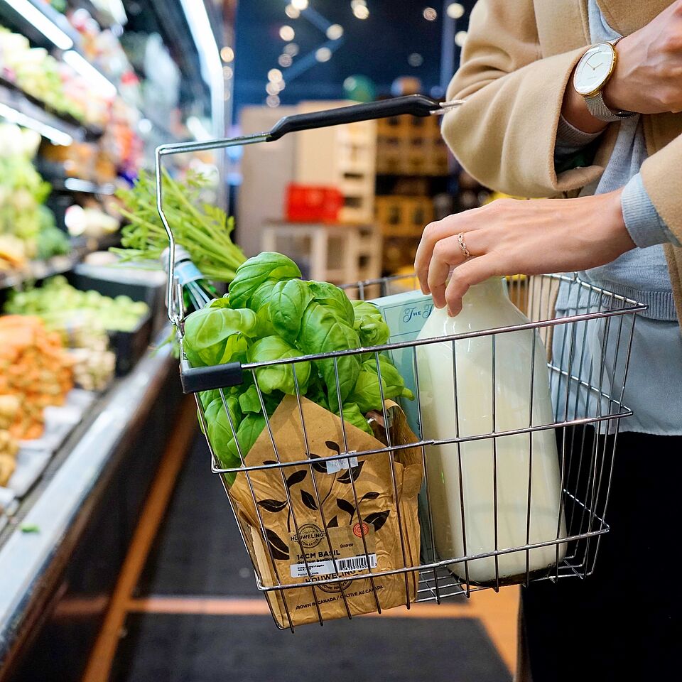Person mit Einkaufskorb und frischen Lebensmitteln im Supermarkt