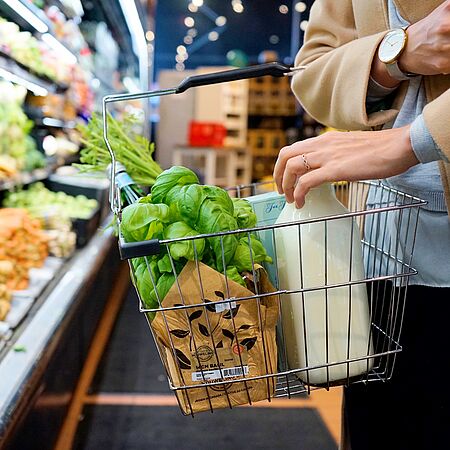 Person mit Einkaufskorb und frischen Lebensmitteln im Supermarkt