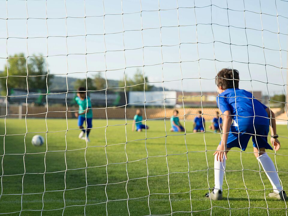 Erste Hilfe Sportunfall Kinder in blauen Trikots spielen Fußball.