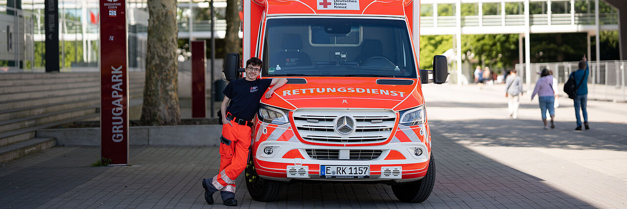 Ein Rettungshelfer lehnt sich an einen Rettungswagen.