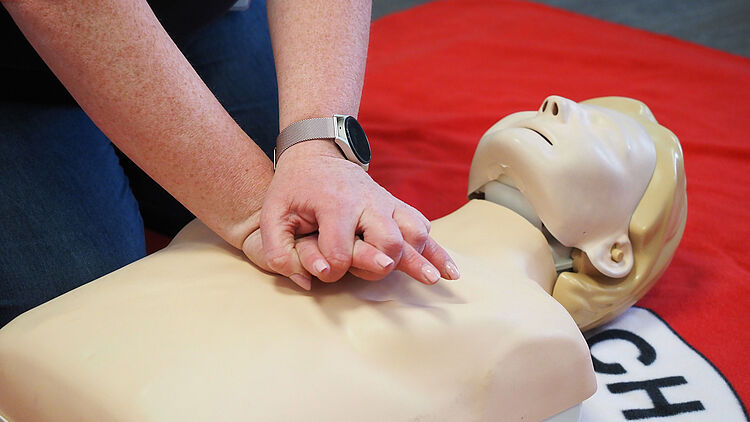 Herzdruck-Massage Hände führen eine Herzdruck-Massage an einer Puppe aus.