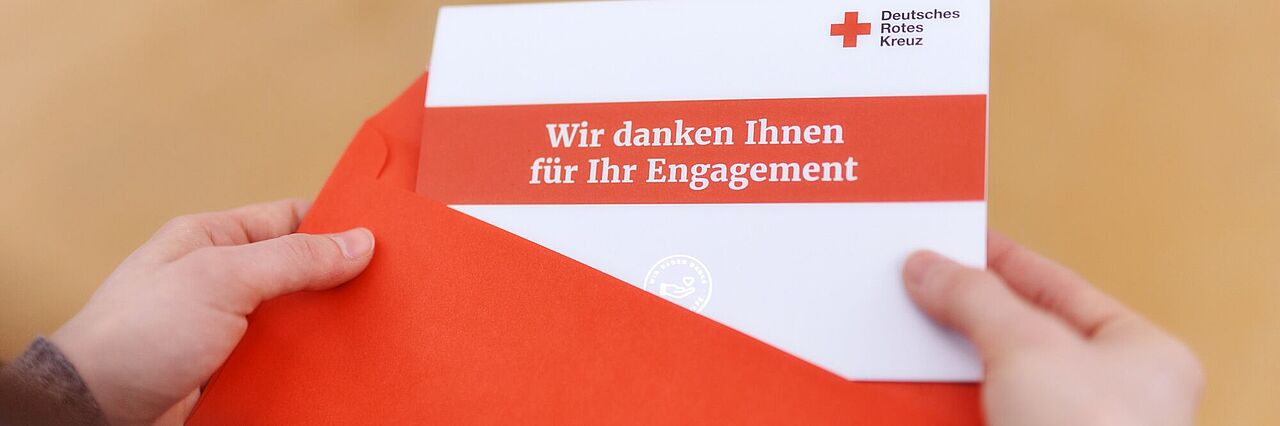 Unternehmenskooperation Jemand zieht eine Karte aus einem Umschlag. Darauf steht "Wir danken Ihnen für Ihr Engagement".