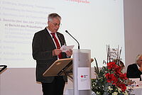 Der Präsident des DRK Essen hält eine Rede hinter einem Rednerpult.