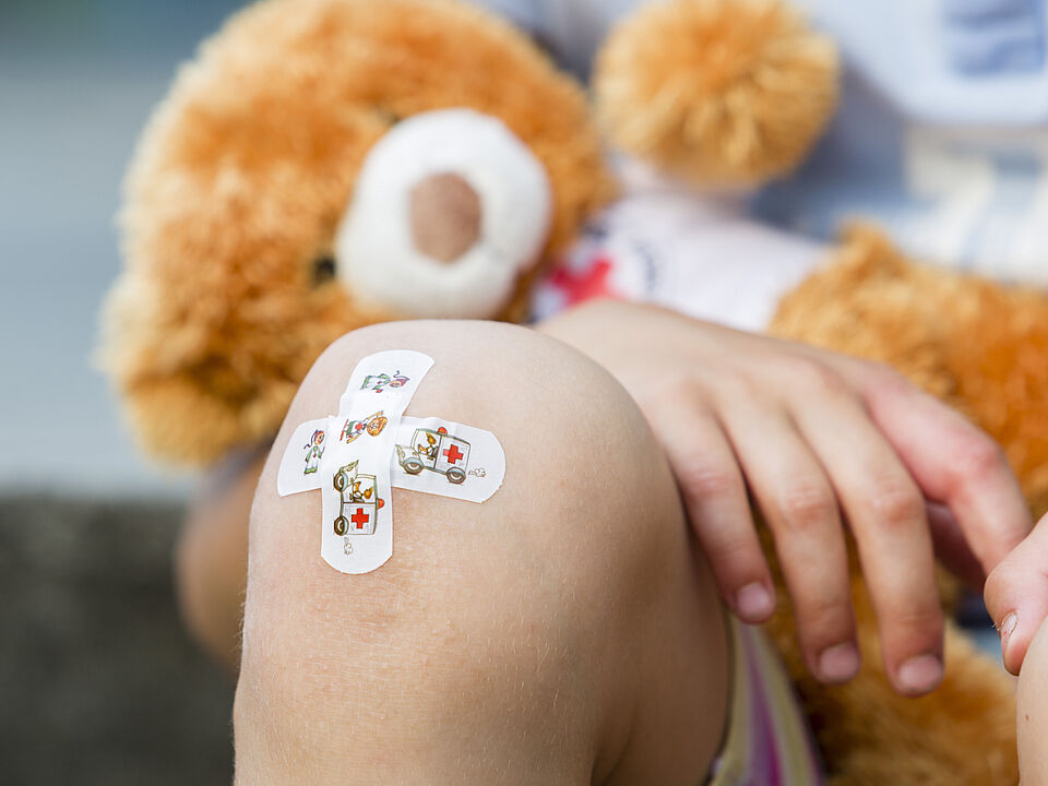 Symbolbild Erste Hilfe am Kind Das Bild zeigt ein Kinderpflaster auf einem Knie eines Kindes.