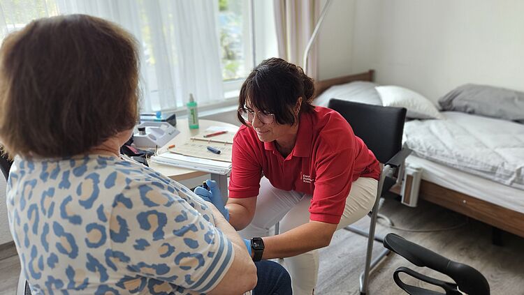Eine Pflegekraft misst den Blutzucker bei einem Gast der Tagespflege.