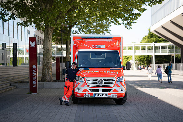 Ein Rettungshelfer des DRK Essen lehnt an einem Rettungswagen.