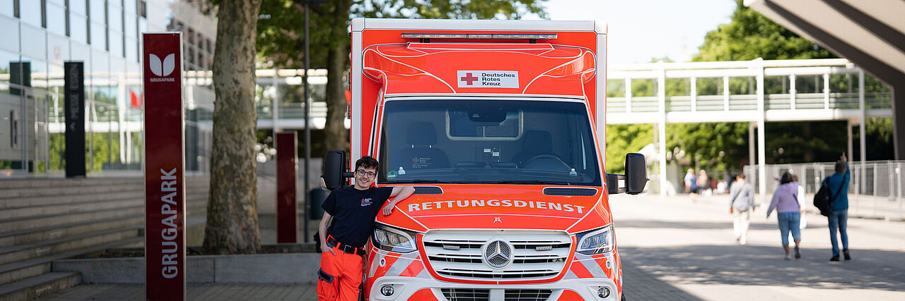 Rettungsdienstschule Ein Rettungshelfer des DRK Essen lehnt an einem Rettungswagen.