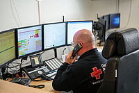 Ein Mann des DRK Essen sitzt in der Einsatzleitzentrale vor mehreren Monitoren und telefoniert.