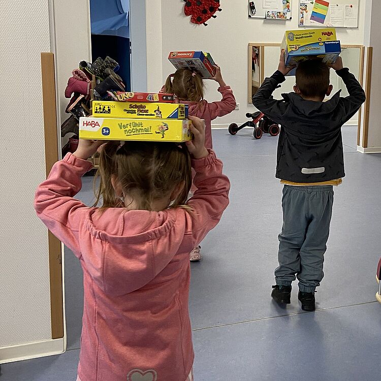 Sachspenden Kinder transportieren Gesellschaftsspiele auf ihren Köpfen.