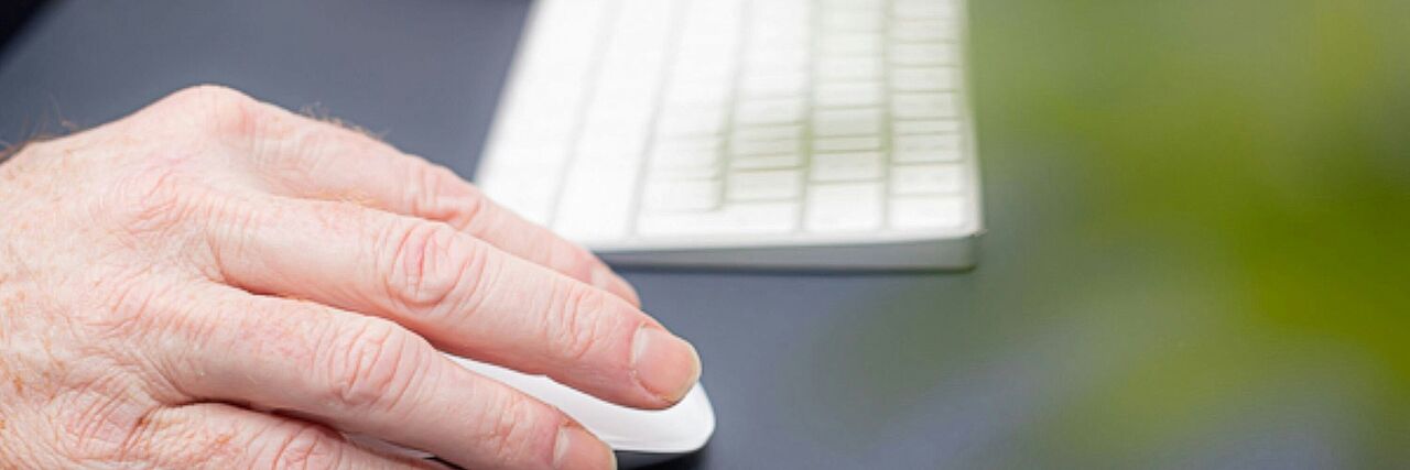 Hände bedienen eine weiße Computer-Tastatur und Maus