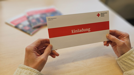 Eine Einladung wird in den Händen gehalten.