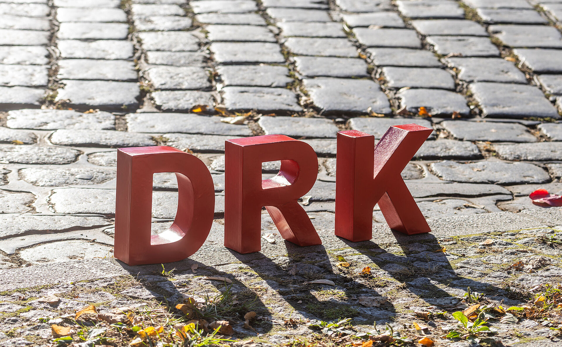 Das DRK in Essen DRK als rote Buchstaben stehen auf einem Kopfsteinpflaster.