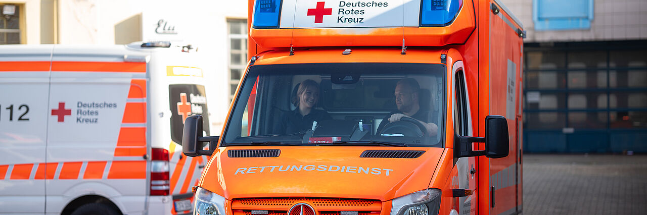 Ein Rettungswagen des DRK Essen fährt los mit Blaulicht. Im Hintergrund sind Gebäude sichtbar.